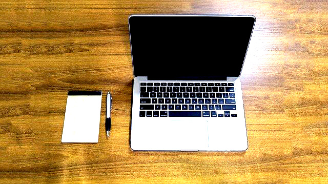 Apple Mac Book Pro on desk with notepad